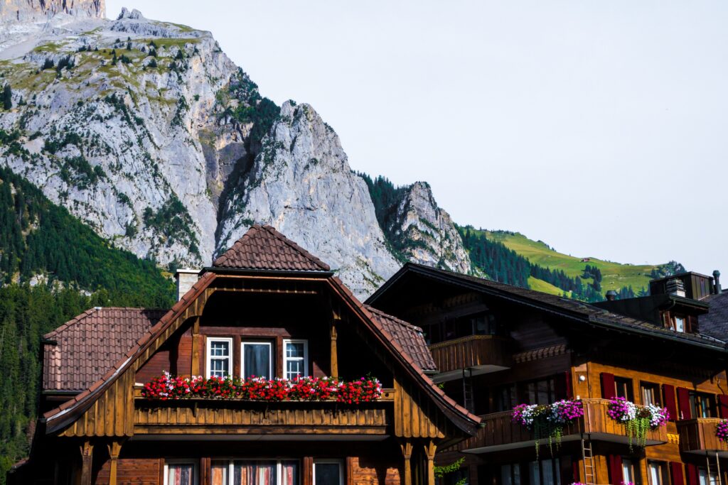 A-frame Alpine house with flowers on balcony and mountain in background