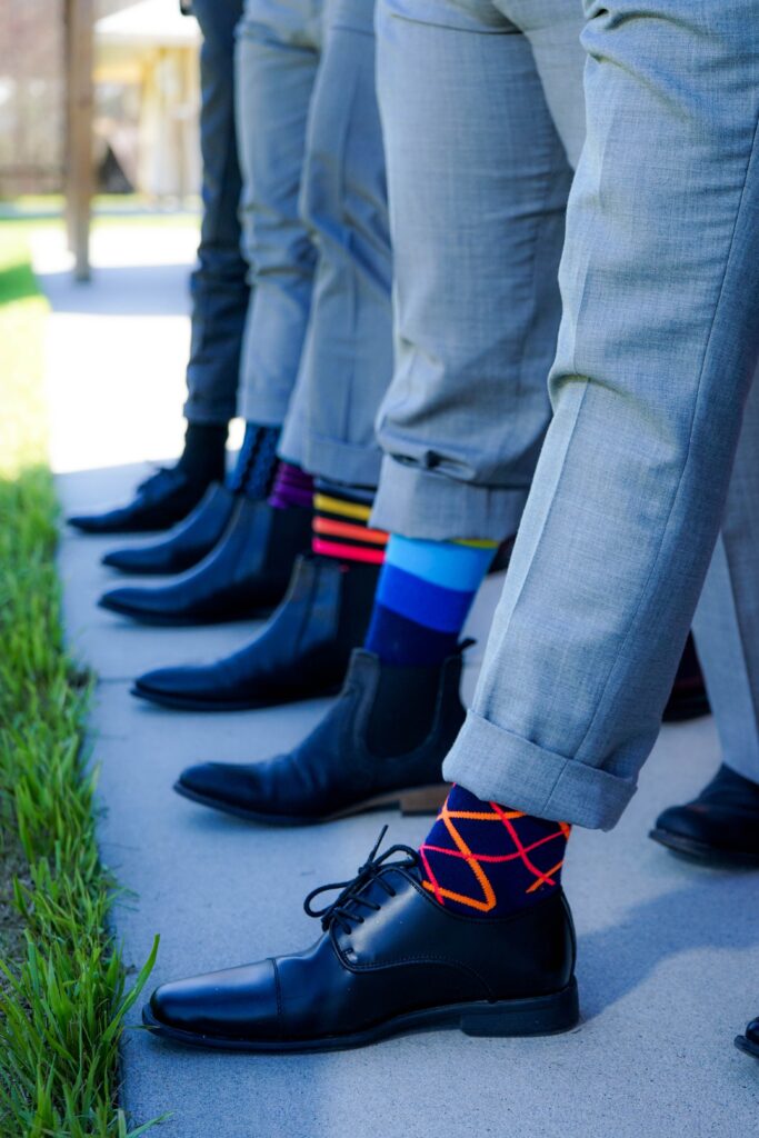 Men's right legs lined up showing colorful socks and black leather shoes