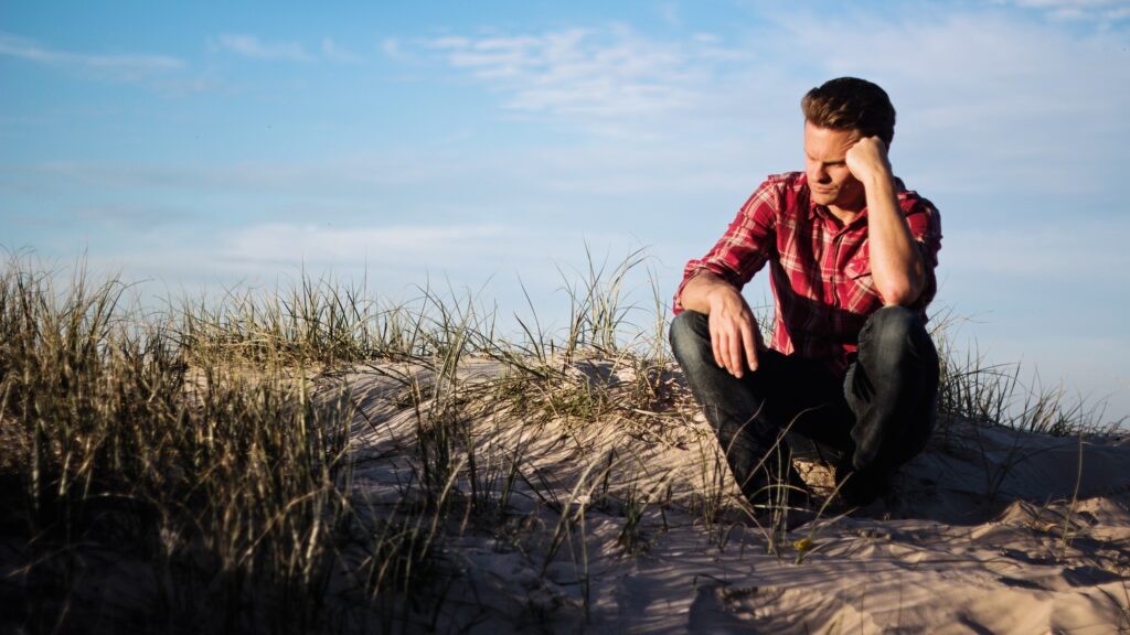 Young man crouching down at edge of beach